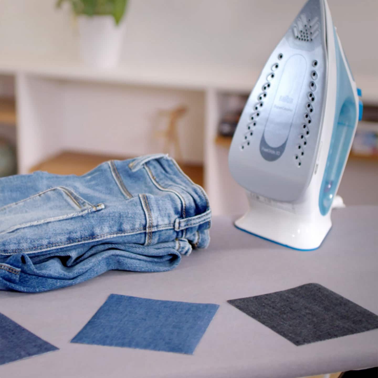 A pair of jeans neatly folded on a table next to an iron