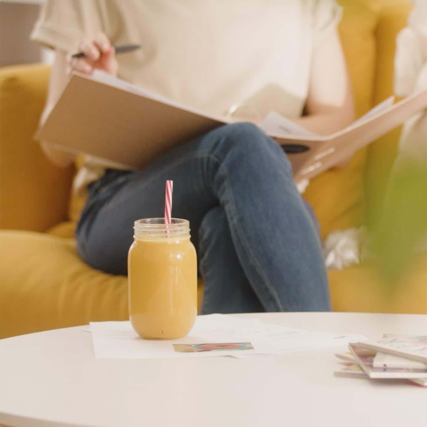 A woman sitting on a couch with a notebook and a glass of juice