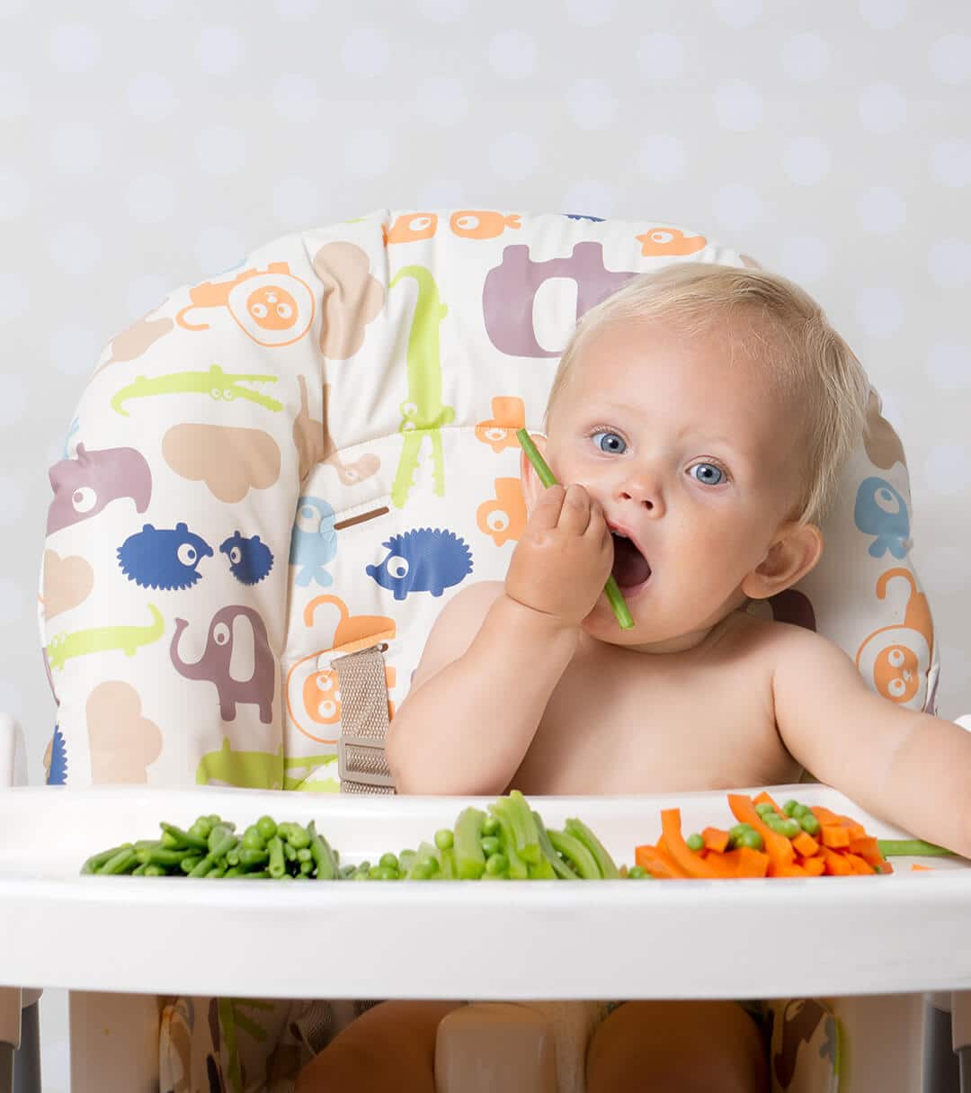Baby sitting in a high chair eating beans