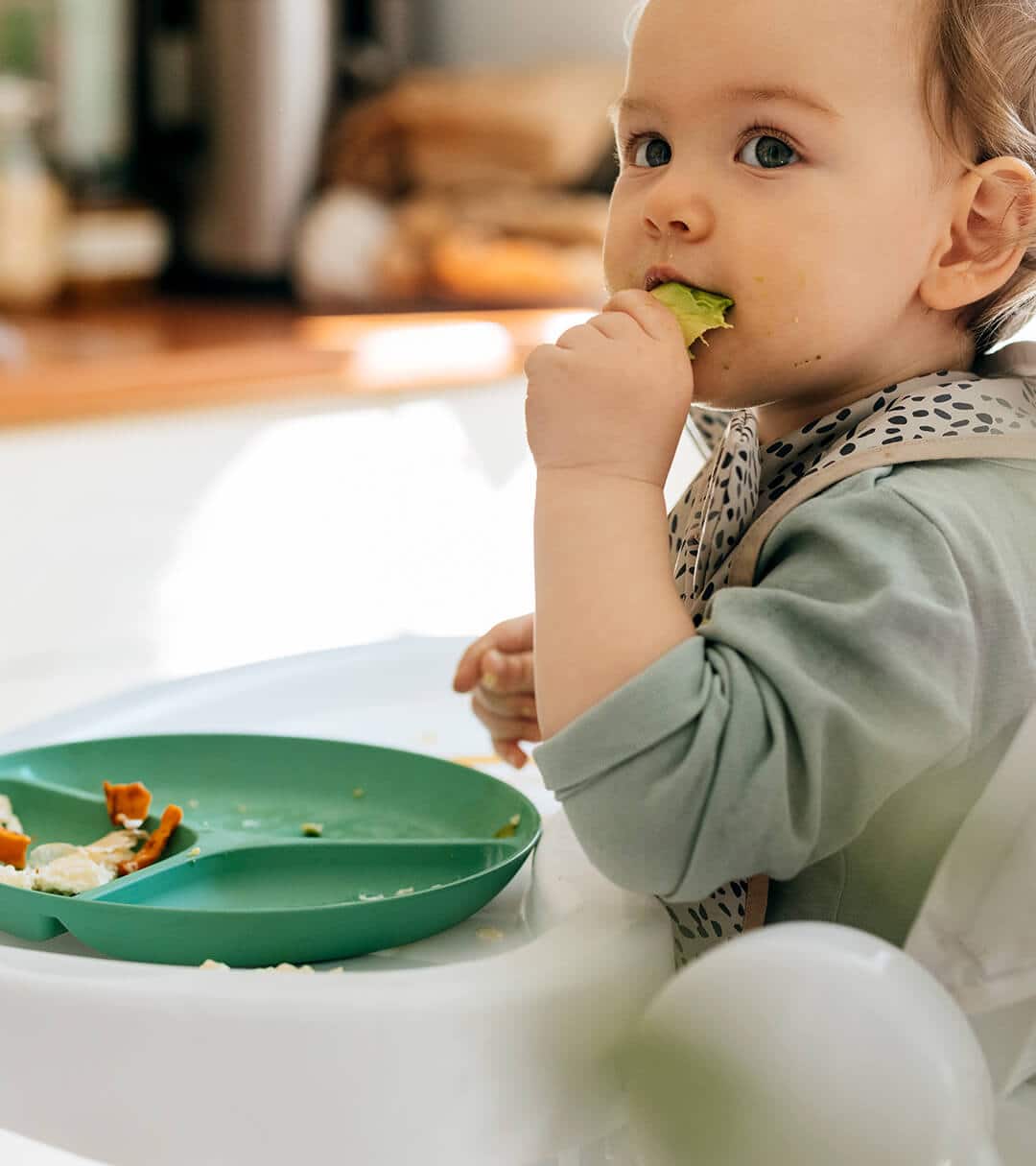 Baby eating food using his hand