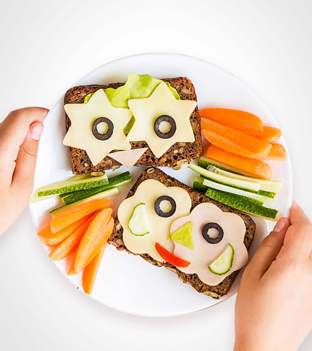 Sandwiches decorated with fun shaped vegetables, ham and cheese