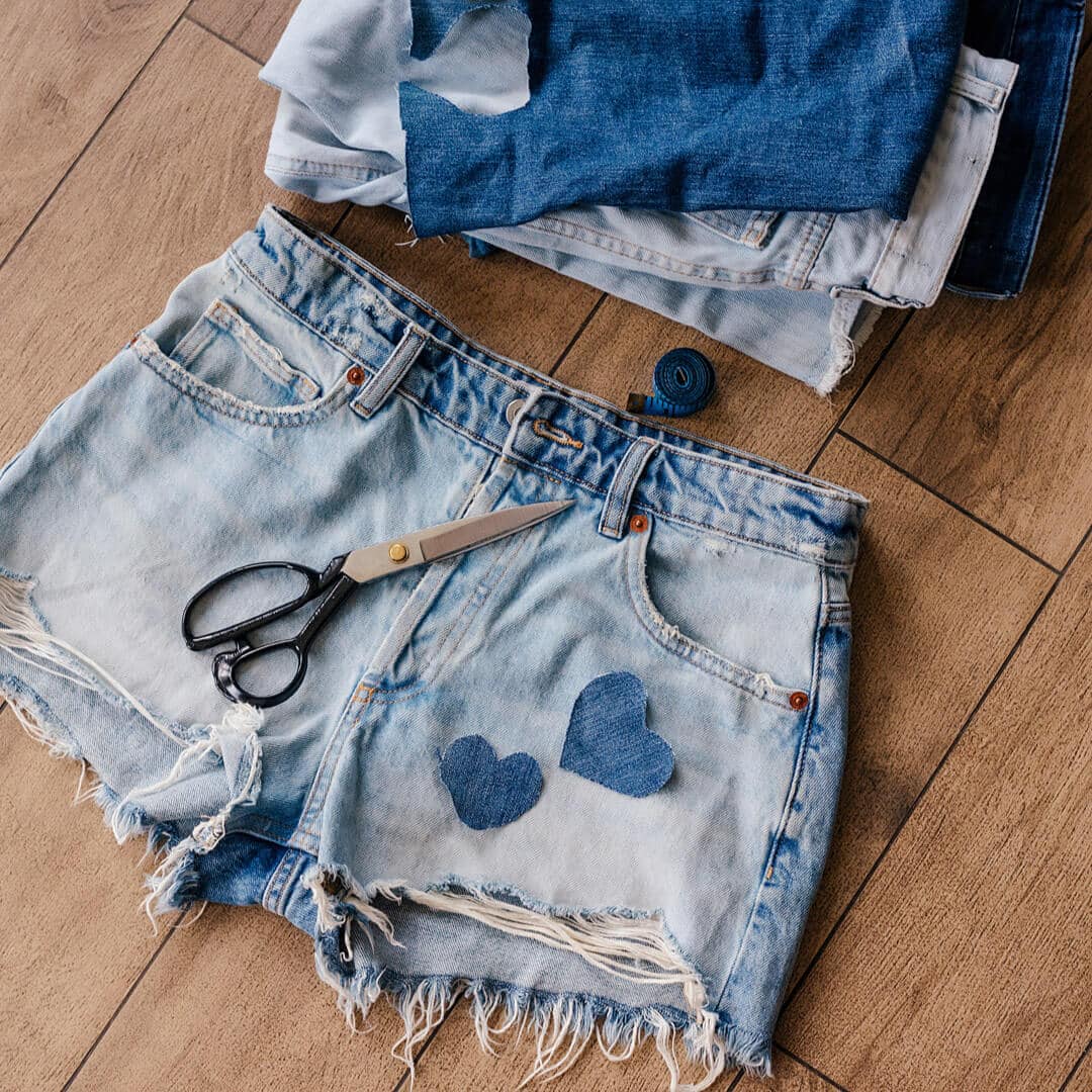 A pair of denim shorts with heart-shaped cutouts and a pair of scissors