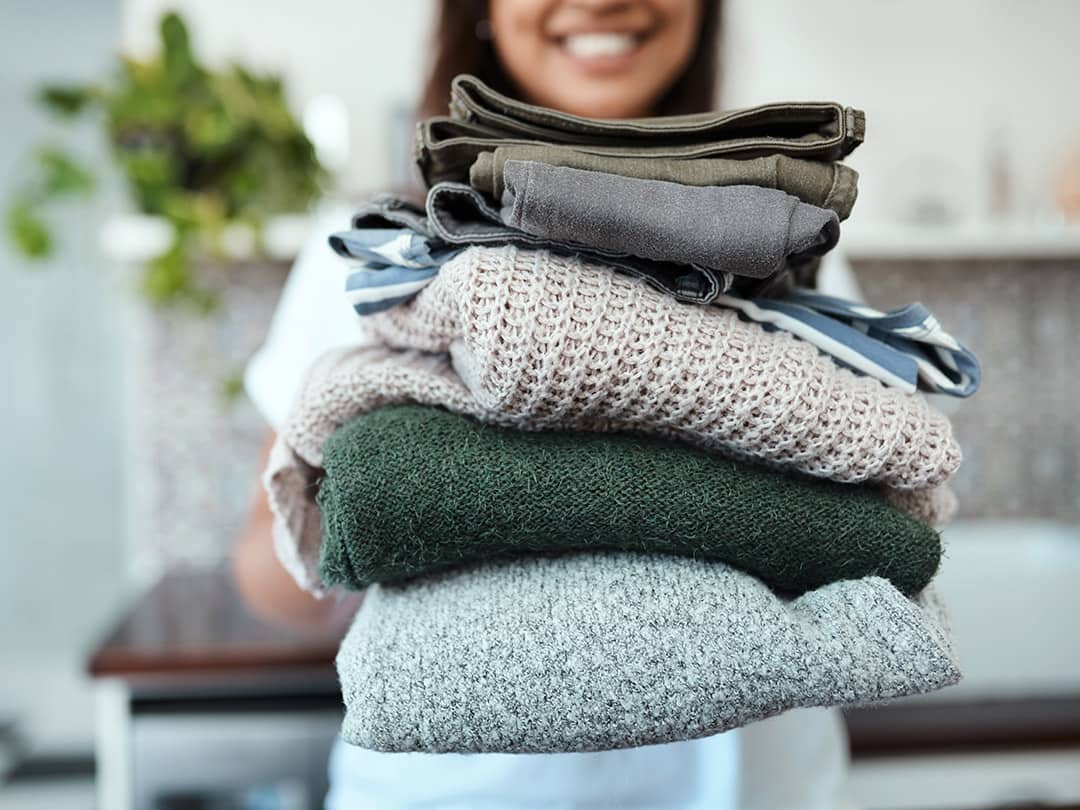 A woman holding a pile of folded laundry