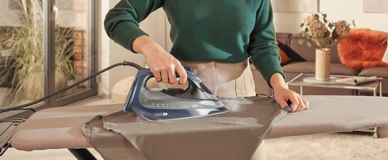 Image of a woman ironing a brow t-shirt with a Braun TexStyle 9 steam iron